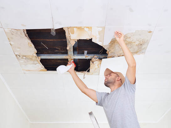 worker spraying the ceiling for water damage restoration, Mississuaga